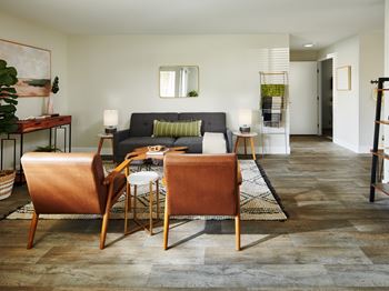A living room with a grey couch and two brown chairs.